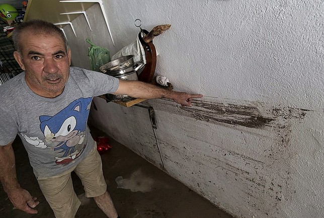 Un vecino marca la altura que alcanzó el agua en el sótano de su vivienda.