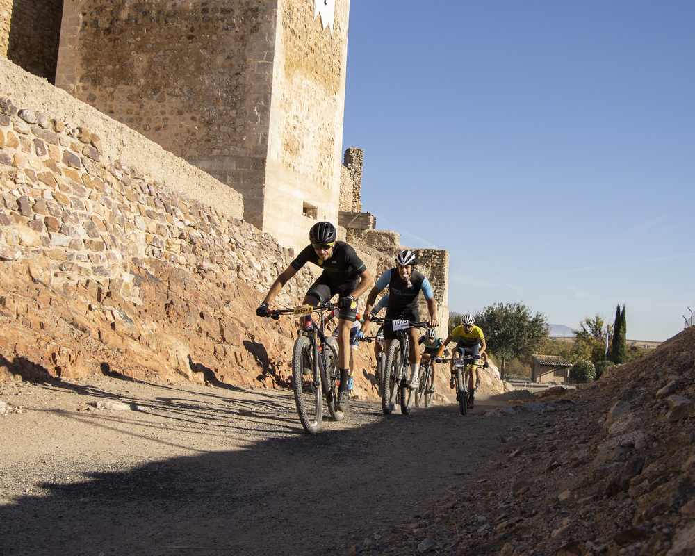 Un grupo de ciclistas pasa junto al Castillo de Calatrava la Vieja. 