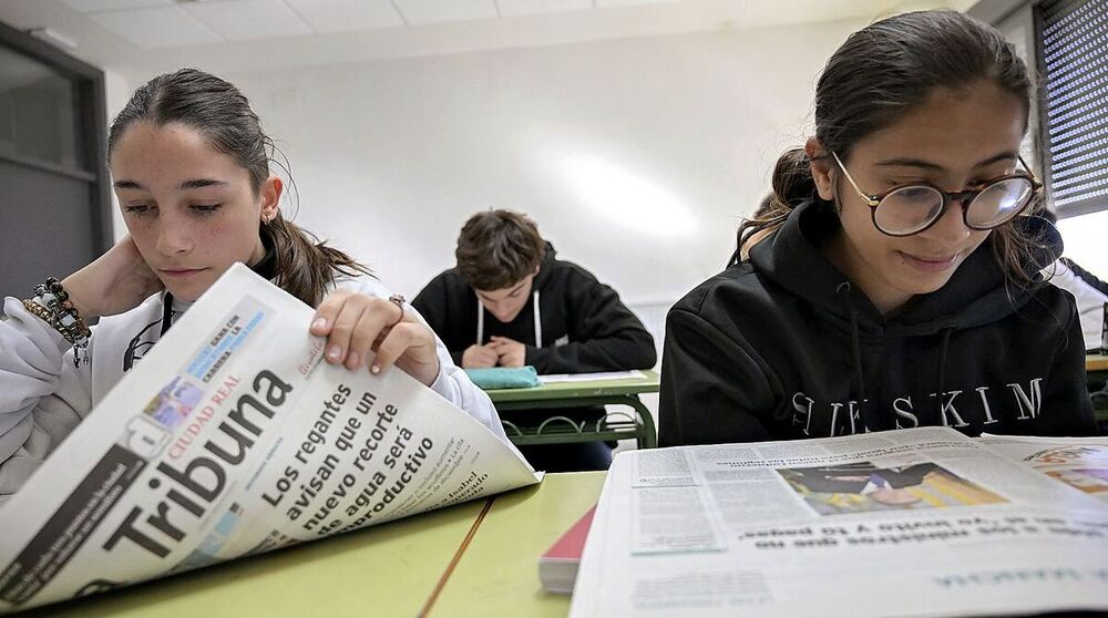 Dos alumnas leen la información del periódico señalada por el profesor